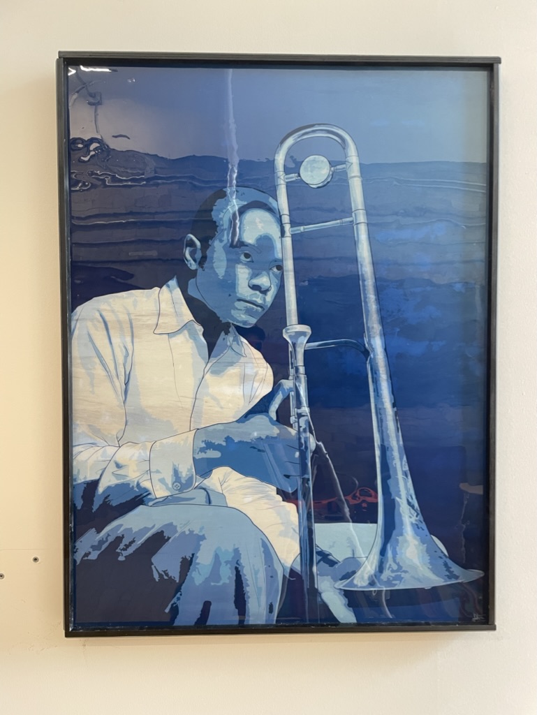 A printed and framed poster of an colorful illustrated poster of jazz trombonist J.J. Johnson
